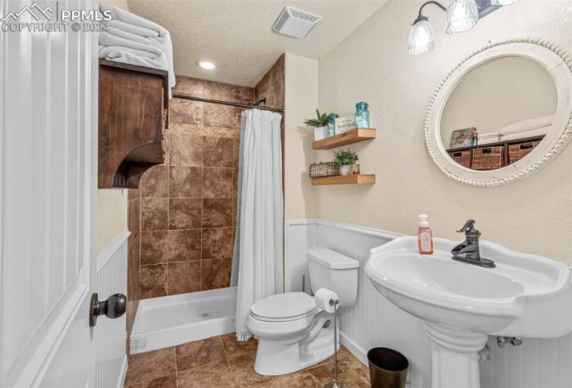 Bathroom featuring curtained shower, tile floors, a textured ceiling, and toilet