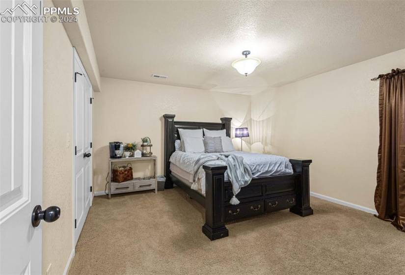 Bedroom with light colored carpet and a textured ceiling