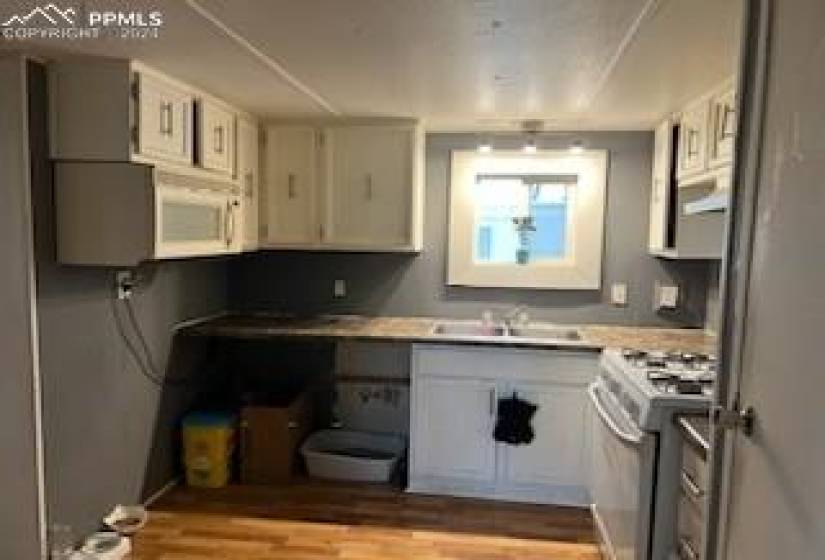 Kitchen featuring white cabinets, light hardwood / wood-style flooring, gas stove, and sink