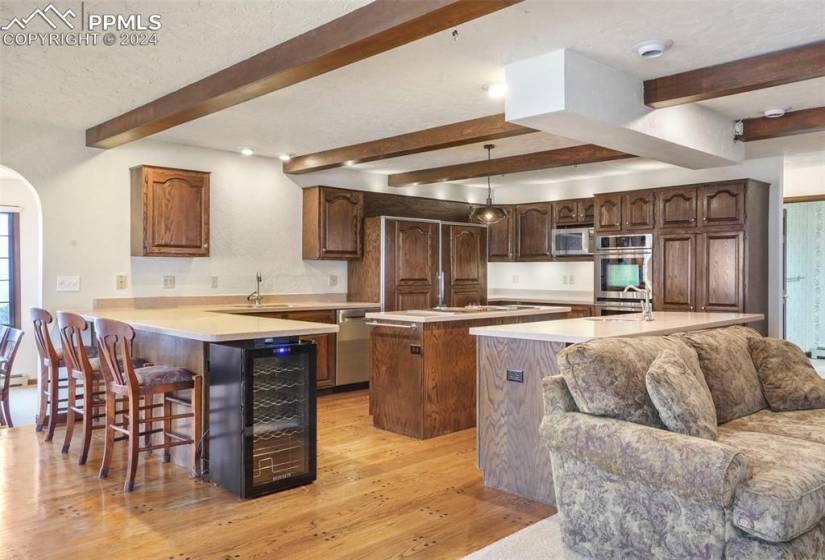 Kitchen featuring light hardwood / wood-style floors, a kitchen island, a breakfast bar, decorative light fixtures, and appliances with stainless steel finishes