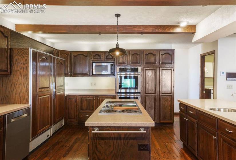 Kitchen featuring a kitchen island, appliances with stainless steel finishes, sink, dark hardwood / wood-style floors, and decorative light fixtures