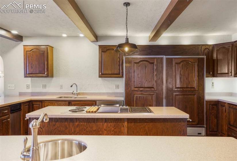 Kitchen with pendant lighting, beam ceiling, a center island, and sink