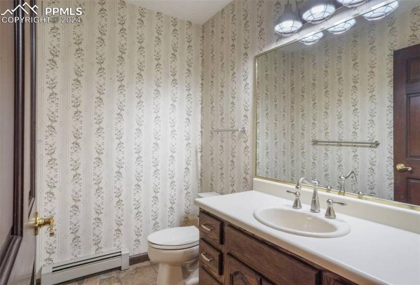 Main Level Bathroom with tile floors, a baseboard heating unit, oversized vanity, and toilet