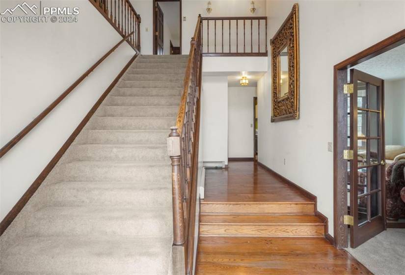 Stairs with dark hardwood / wood-style flooring, a towering ceiling, and a baseboard radiator