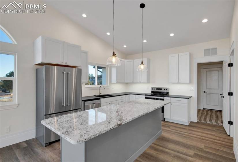 Kitchen featuring a kitchen island, dark hardwood / wood-style flooring, stainless steel appliances, and white cabinets