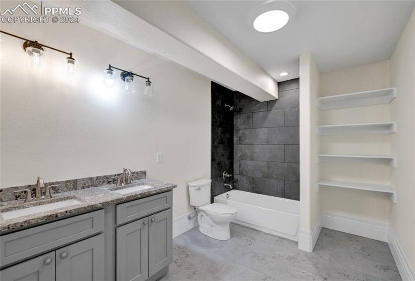 Full bathroom featuring toilet, double sink vanity, tiled shower / bath combo, and tile flooring