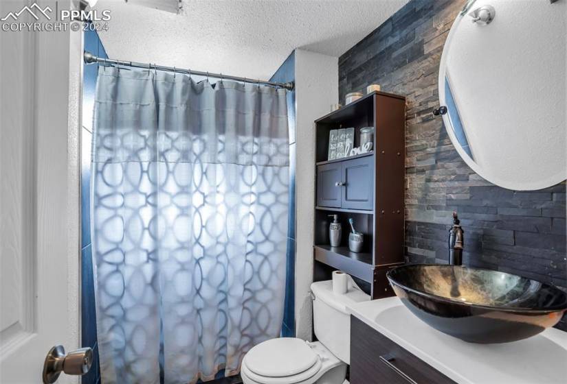 Lower bathroom with vanity, toilet, and a textured ceiling
