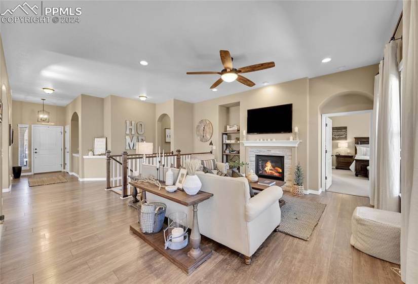 Living room featuring light hardwood / wood-style flooring, a fireplace, ceiling fan, and built in features