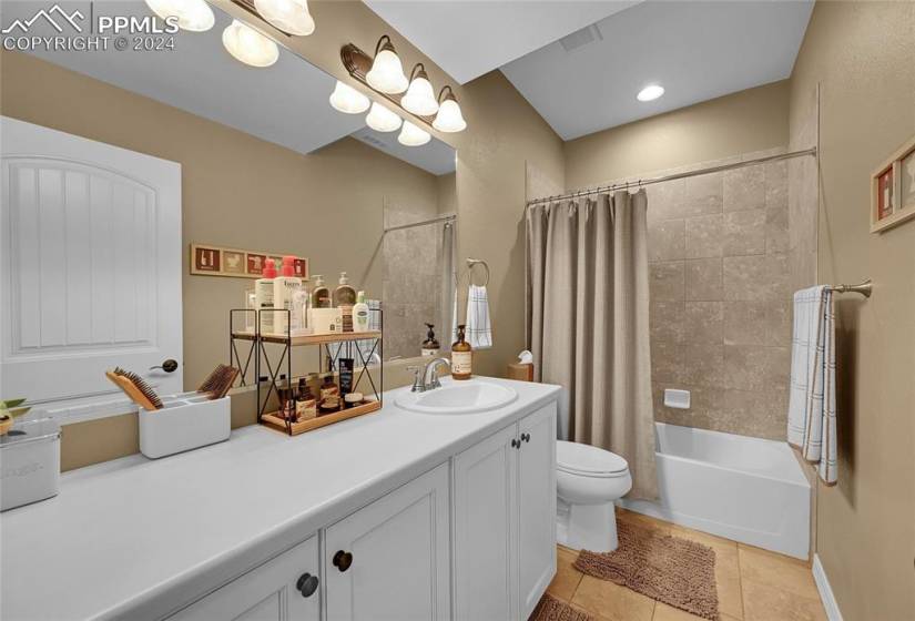 Full bathroom with shower / bath combo with shower curtain, tile floors, vanity, and toilet