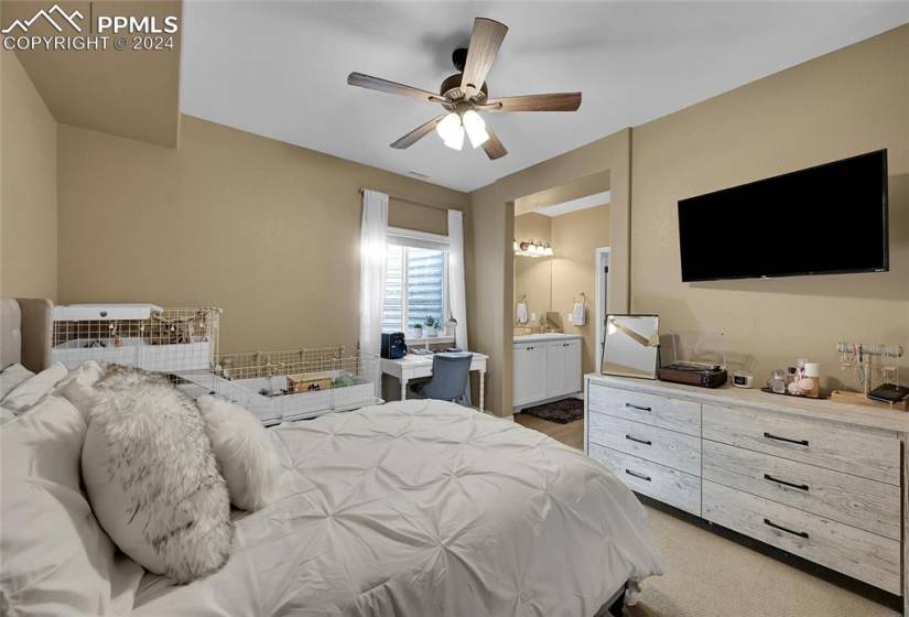 Bedroom featuring ensuite bath, carpet floors, and ceiling fan