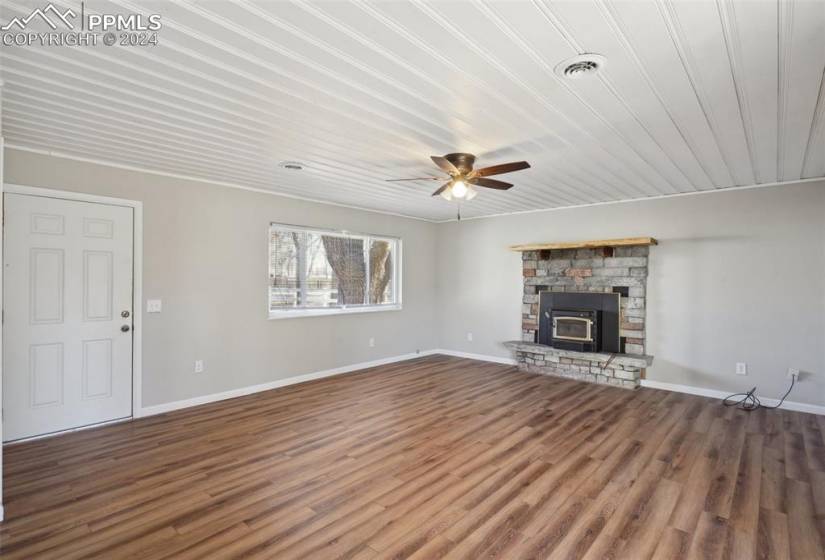 Unfurnished living room featuring a fireplace, dark hardwood / wood-style floors, ceiling fan, and crown molding