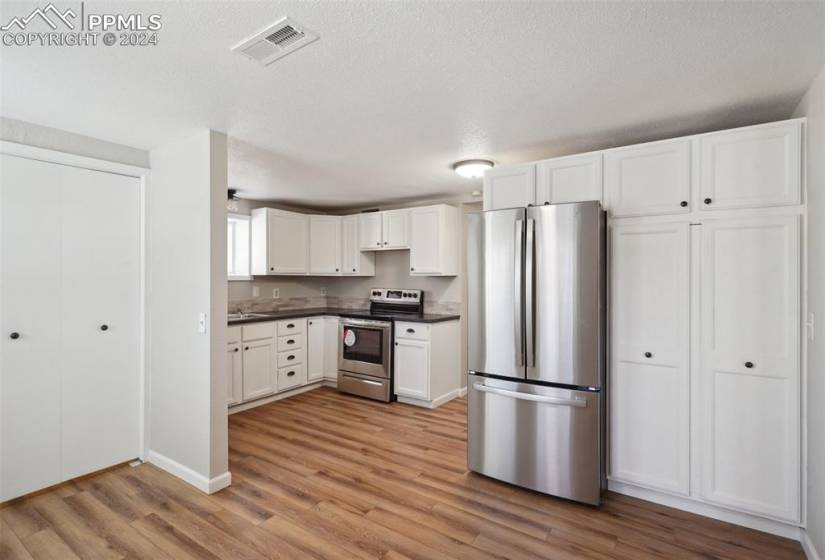 Kitchen featuring sink, hardwood / wood-style flooring, stainless steel appliances, and white cabinets