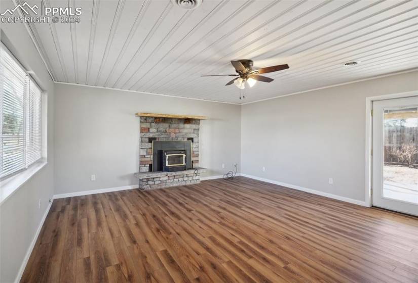 Unfurnished living room featuring dark hardwood / wood-style flooring, crown molding, ceiling fan, and a healthy amount of sunlight
