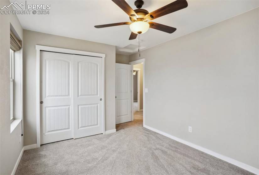 Unfurnished bedroom featuring light carpet, ceiling fan, and a closet