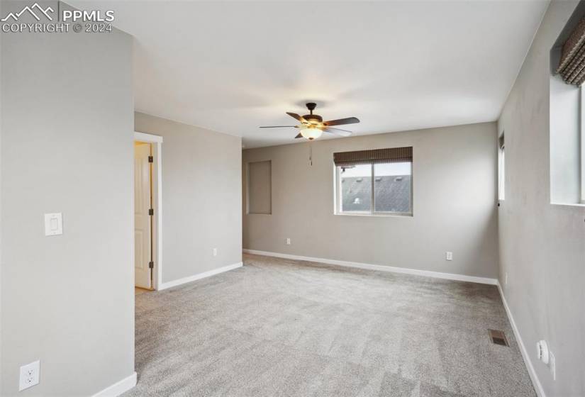 Empty room with ceiling fan and light carpet