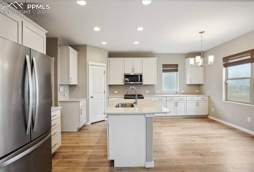 Kitchen with sink, appliances with stainless steel finishes, light hardwood / wood-style flooring, and white cabinets