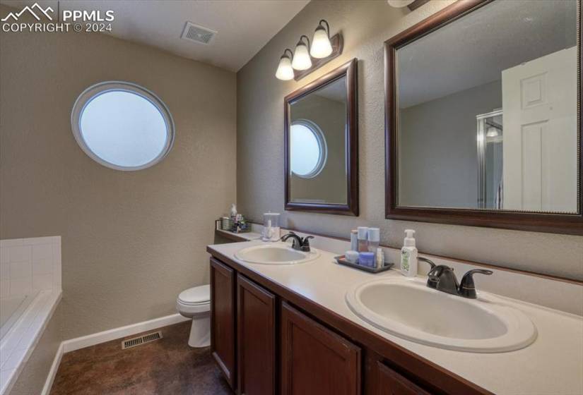 Upper Level Primary Owner's Bathroom with dual sink vanity, framed mirrors, and tub/shower.