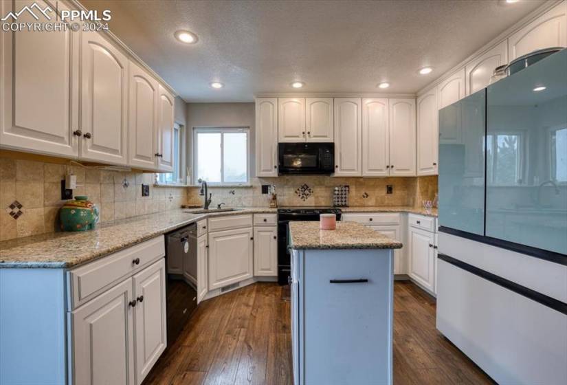 The Island Kitchen offers abundant white cabinets w/ granite countertops and tile backsplash.