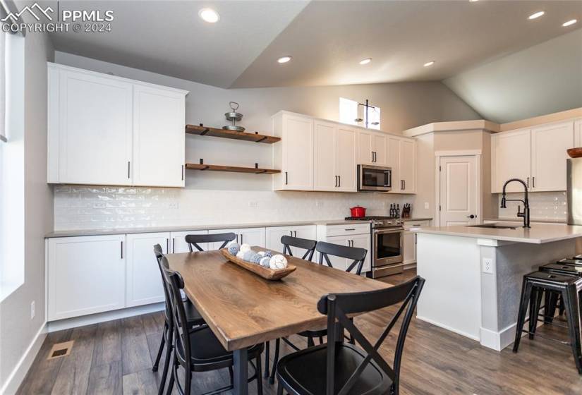 Kitchen with white cabinetry, dark hardwood / wood-style flooring, stainless steel appliances, and tasteful backsplash
