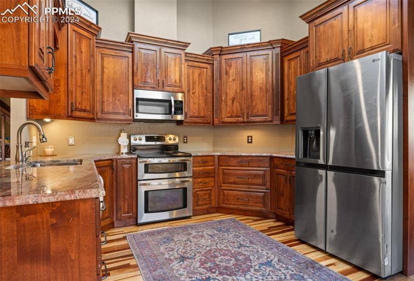 Kitchen featuring light hardwood / wood-style floors, stainless steel appliances, a high ceiling, and sink