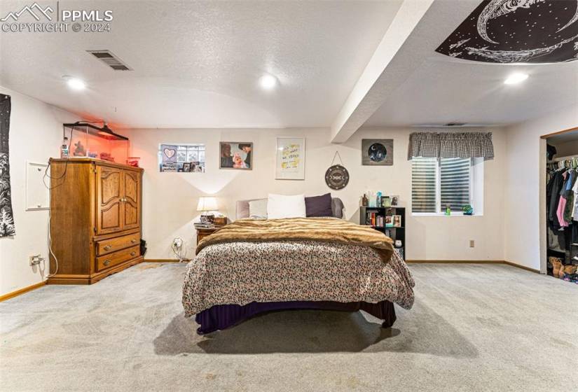 Bedroom with a closet, a spacious closet, light carpet, and a textured ceiling