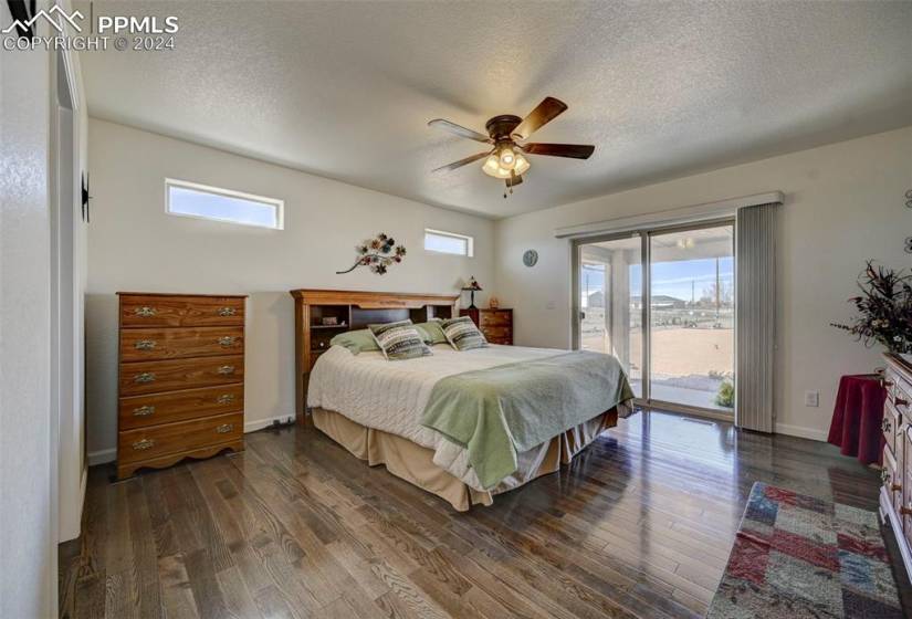 Bedroom featuring access to exterior, ceiling fan, a textured ceiling, and dark hardwood / wood-style flooring
