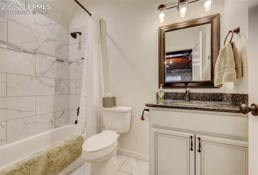 Full bathroom with shower / bath combo, vanity, tile flooring, and toilet