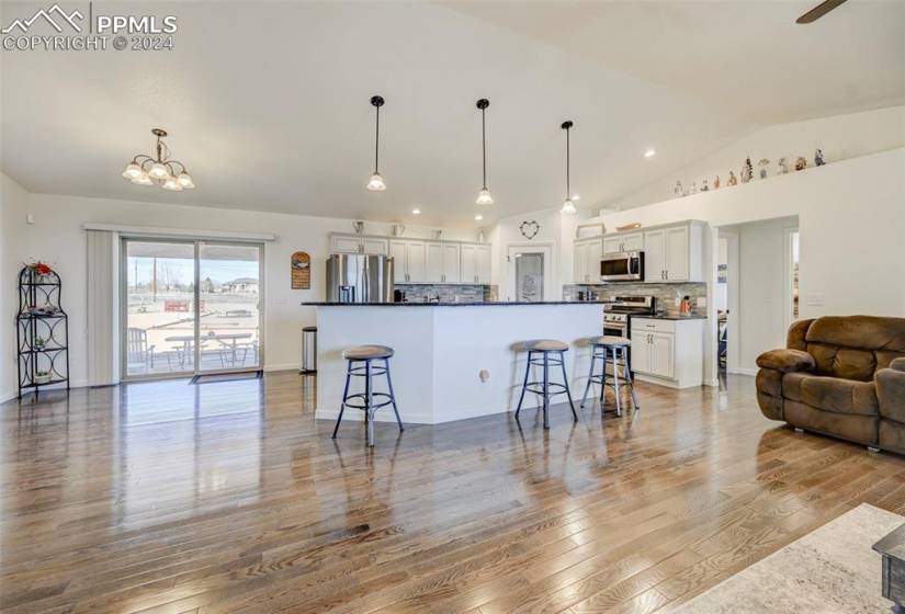 Kitchen featuring white cabinets, a breakfast bar area, tasteful backsplash, appliances with stainless steel finishes, and decorative light fixtures