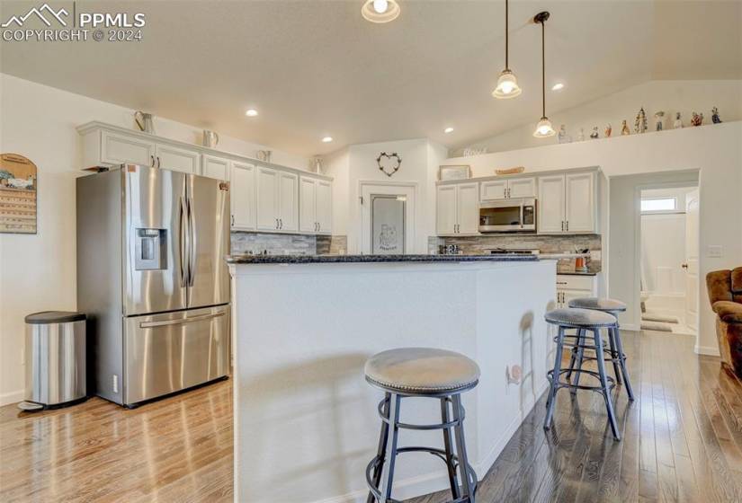 Kitchen featuring hanging light fixtures, appliances with stainless steel finishes, light hardwood / wood-style floors, and tasteful backsplash