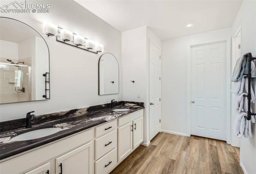 Bathroom featuring a shower with door, wood-type flooring, and double sink vanity