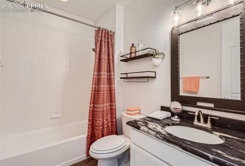 Full bathroom featuring hardwood / wood-style flooring, shower / bath combination with curtain, vanity, and toilet