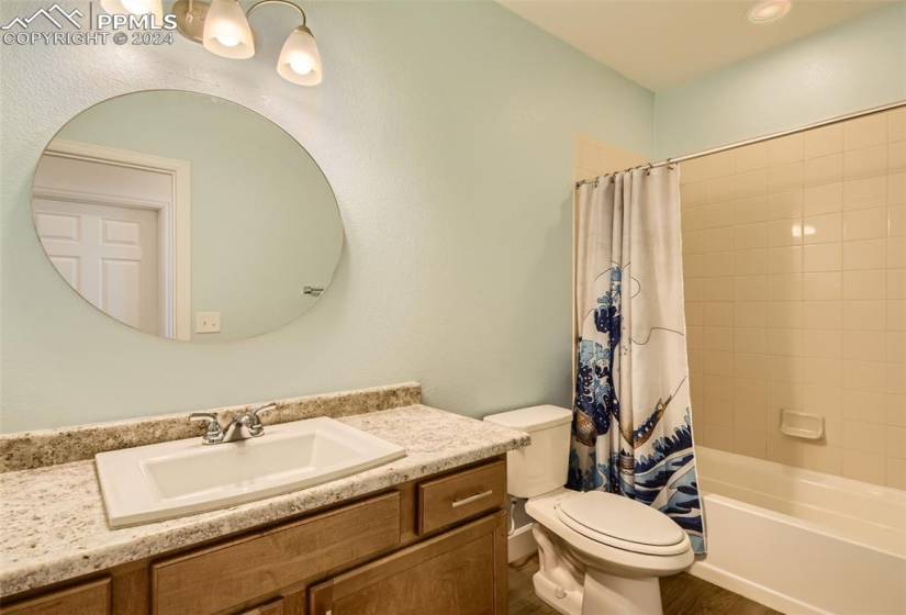 Full bathroom with hardwood / wood-style floors, shower / bath combination with curtain, vanity, and toilet