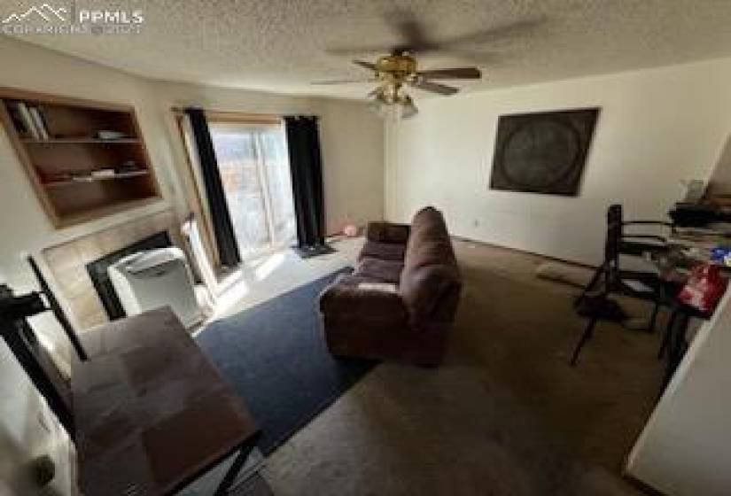 Living room featuring dark colored carpet, ceiling fan, a textured ceiling, and built in features