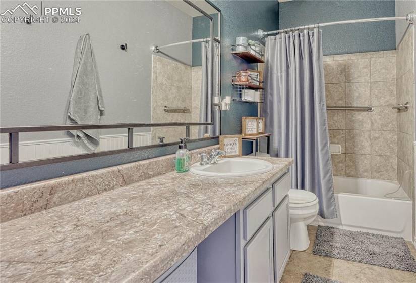 Full bathroom featuring toilet, shower / tub combo with curtain, tile floors, and vanity