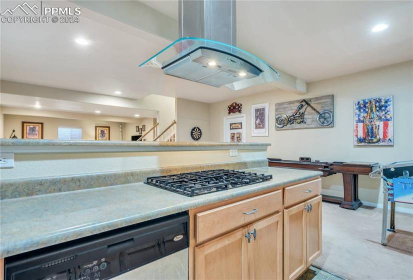 Lower level kitchen with gas stovetop, vent, DW, and room for a refrigerator