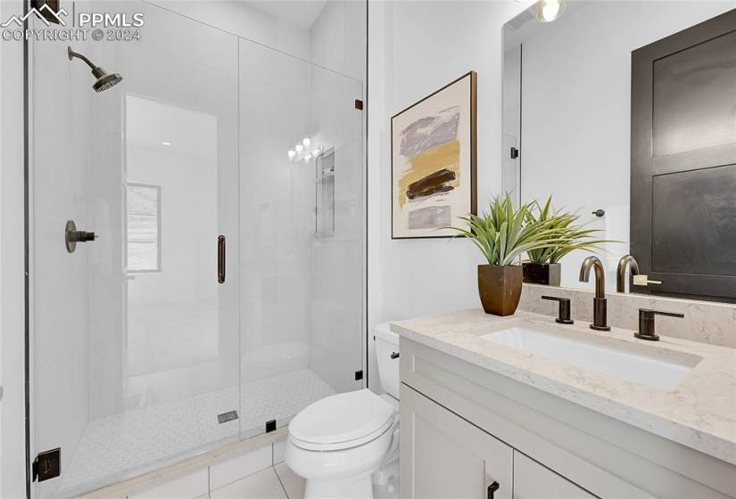 Bathroom featuring toilet, tile floors, walk in shower, and vanity with extensive cabinet space