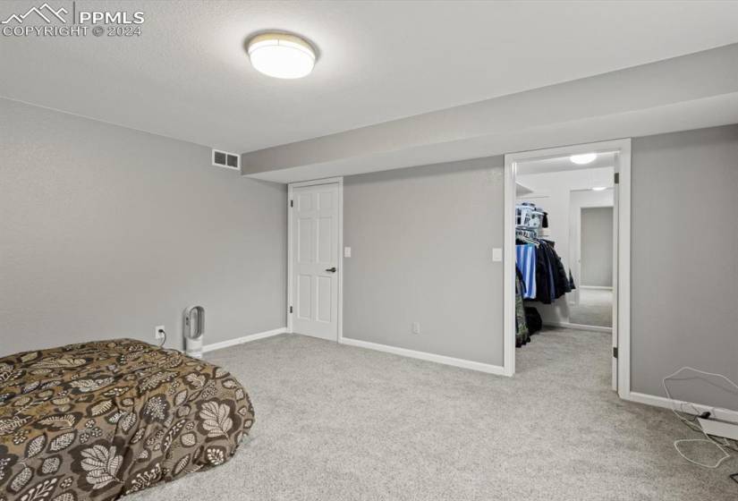 Bedroom with a walk in closet, light colored carpet, and a closet