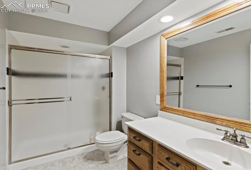 Bathroom featuring tile floors, an enclosed shower, oversized vanity, and toilet