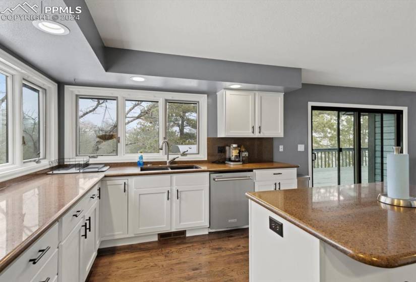 Kitchen featuring hardwood floors, stainless steel dishwasher, a healthy amount of sunlight and walks out to the deck.