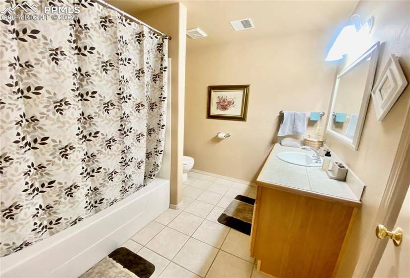 Full bathroom featuring vanity, toilet, shower / bath combination with curtain, and tile flooring