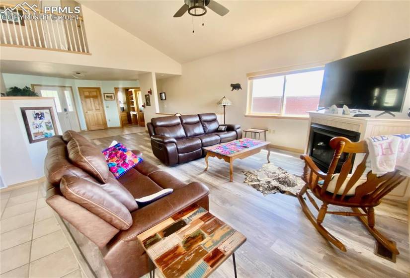 Living room featuring light hardwood / wood-style flooring, high vaulted ceiling, and ceiling fan