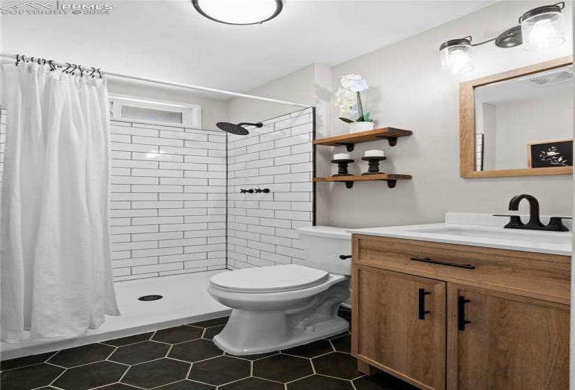 Bathroom with curtained shower, tile floors, vanity, and toilet