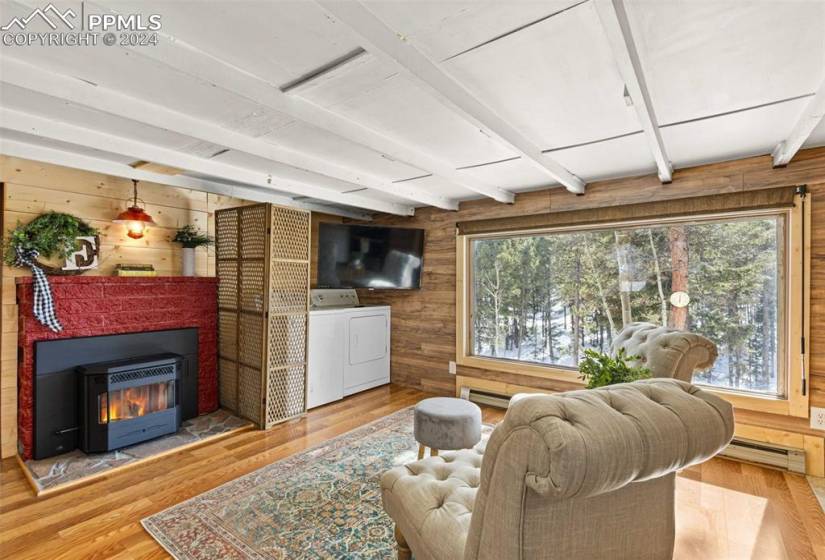 Living room with beam ceiling, washer / clothes dryer, wood walls, and light hardwood / wood-style floors