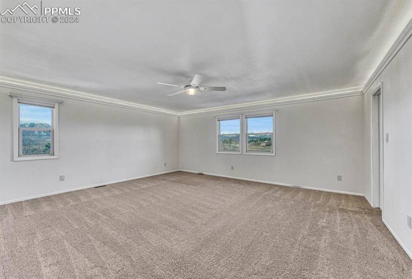 Empty room featuring light carpet, ceiling fan, and ornamental molding