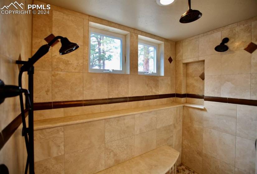 Stunning spa shower with multiple heads, bench seat and a window to enjoy the scenery outside!!