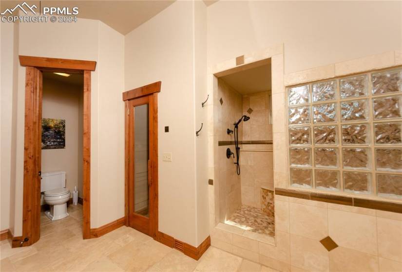 Bathroom with tiled shower, tile flooring, and toilet