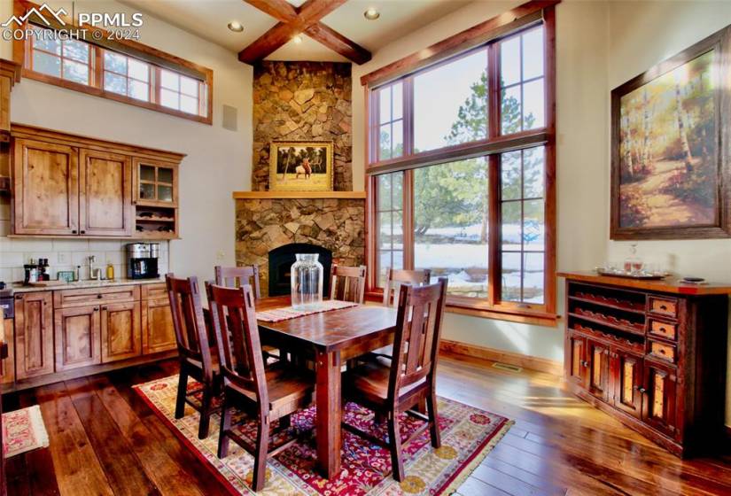 Dining area featuring a fireplace, dark hardwood floors, plenty of natural light, and a high beamed ceiling
