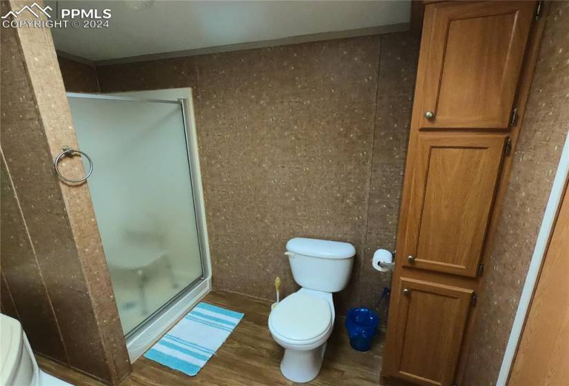 Bathroom featuring toilet, hardwood / wood-style floors, and a shower with shower door