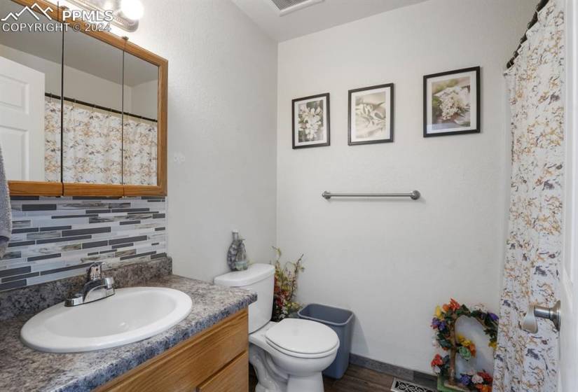 Bathroom with tasteful backsplash, toilet, vanity, and wood-type flooring