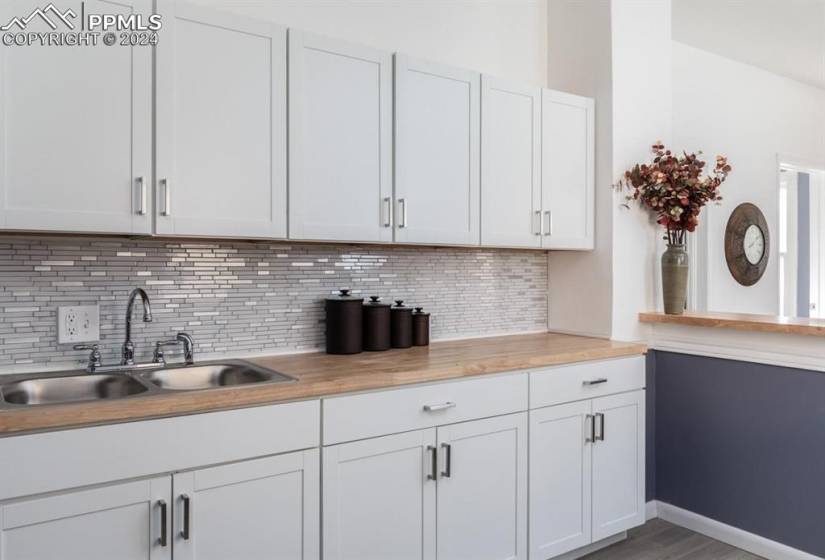 Kitchen featuring white cabinets, sink, wood-type flooring, and tasteful backsplash